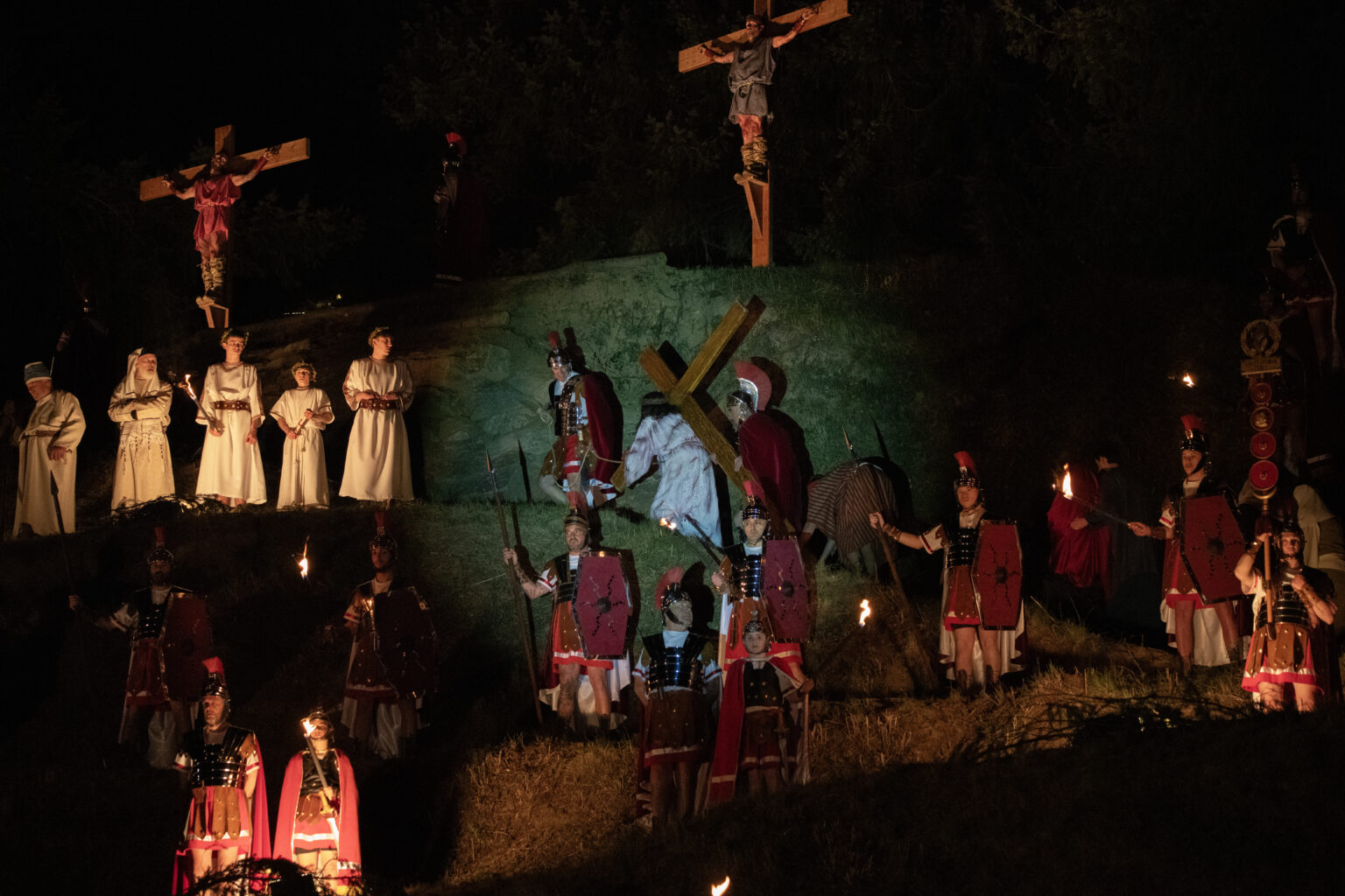 Escena nocturna de la Via Crucis Vivent: Jesús carrega la creu entre soldats romans i figurants amb torxes.